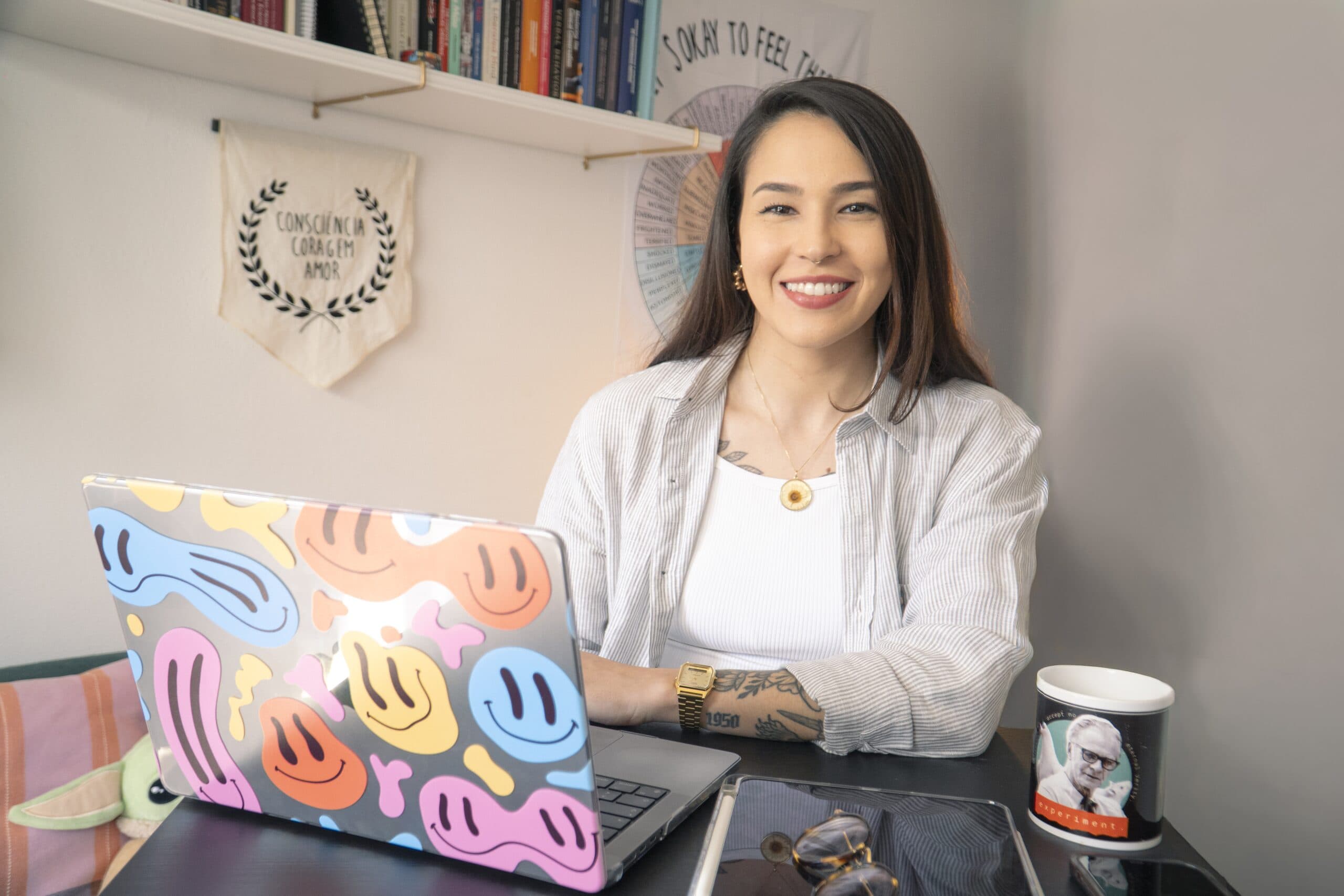 A psicóloga Danielle Liz Rossignoli sentada no seu consultório, sorrindo